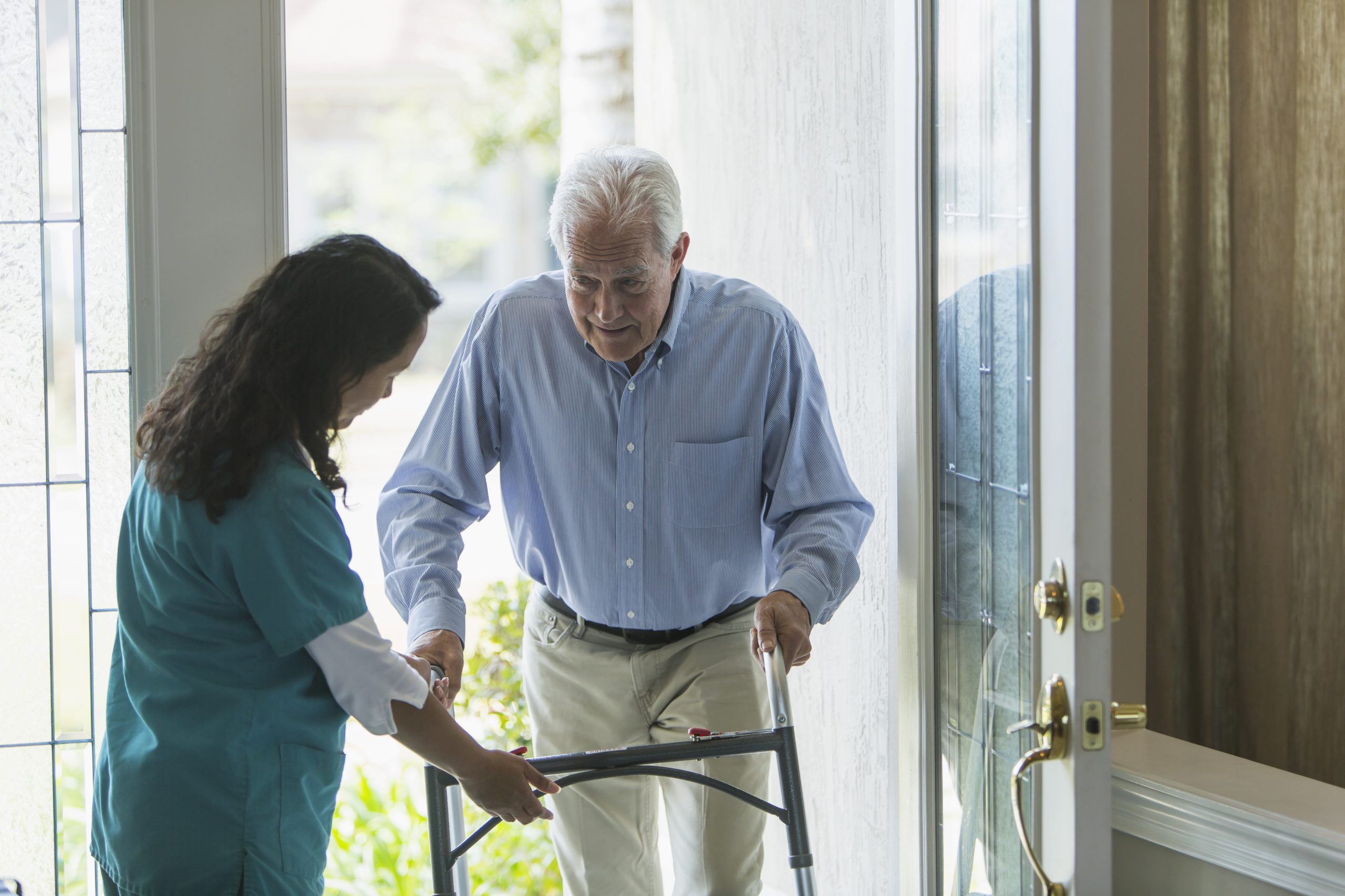 Home healthcare worker helping elderly man with walker